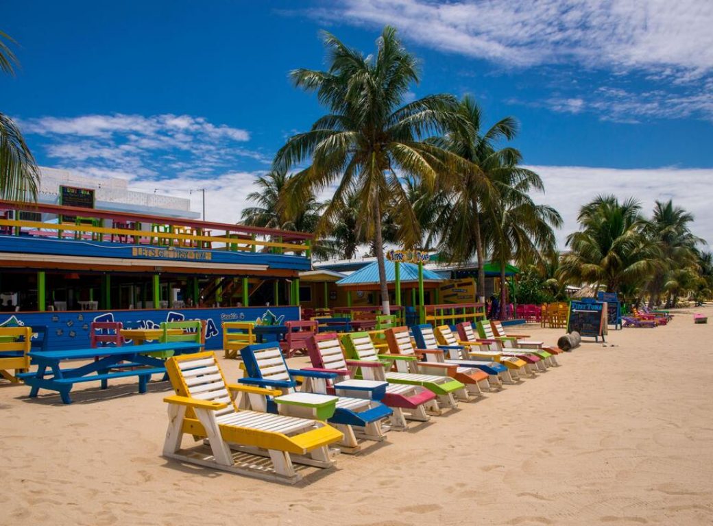 2D6P720 PLACENCIA, STANN CREEK DISTRICT / BELIZE - JUNE 2018: Colourful wooden sun beds outside the beachfront Tipsy Tuna bar on Placencia Beach, Belize.